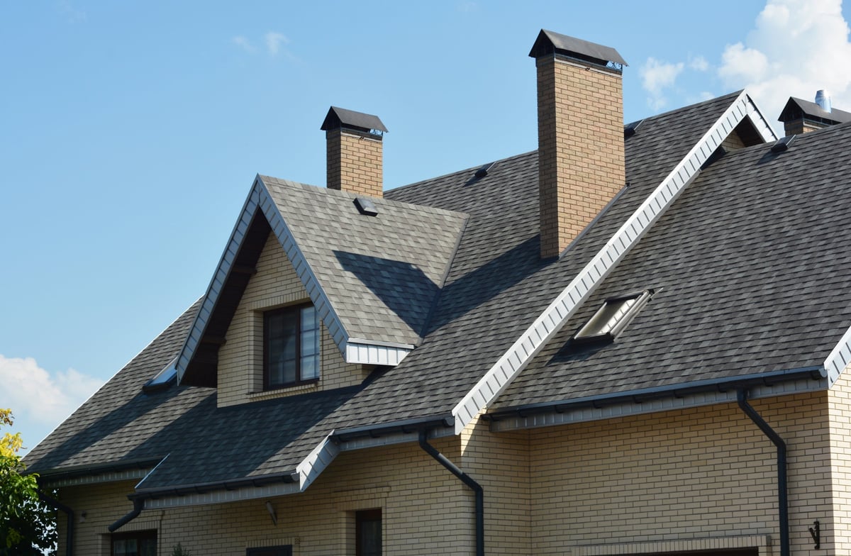 Close view of asphalt shingle rooftop with dormer window, skylights and roof vents