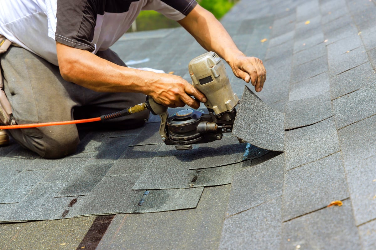 Roofing nails being installed into new shingles with a pneumatic nail gun